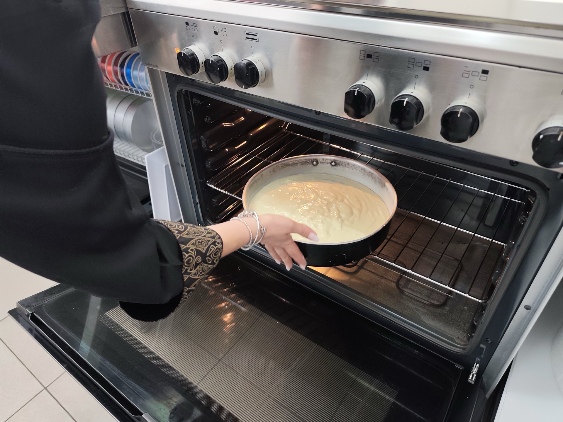 Tortiera con composto chiaro appena inserita nel forno, in una fase di cottura del pan di Spagna. La foto documenta un momento operativo del laboratorio di pasticceria di Viglianisi Catering.