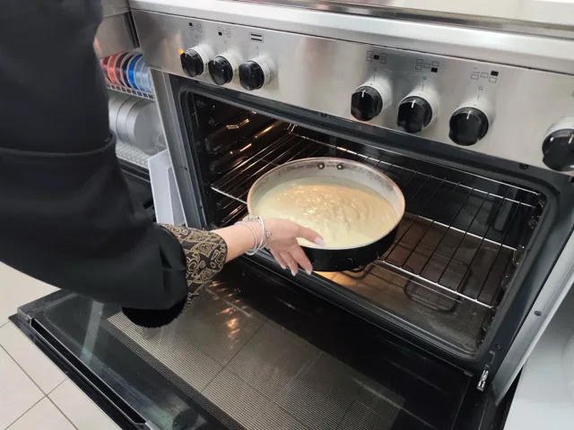 Tortiera con composto chiaro appena inserita nel forno, in una fase di cottura del pan di Spagna. La foto documenta un momento operativo del laboratorio di pasticceria di Viglianisi Catering.