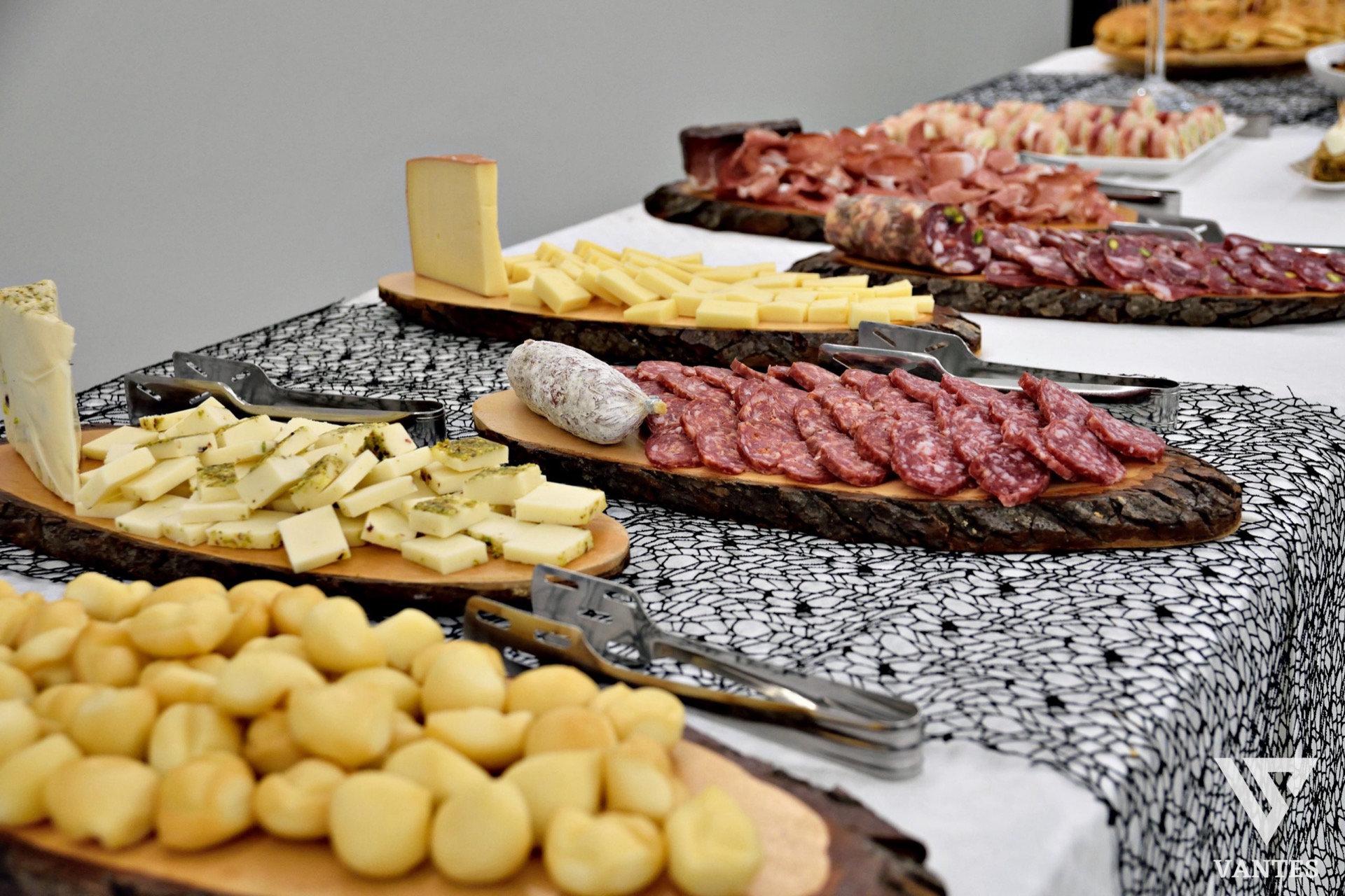 Banchetto catering con salumi, formaggi e piccoli gnocchetti disposti su taglieri rustici di legno. La presentazione è ricca e ordinata, ideale per un buffet di antipasti o aperitivo di cerimonia.